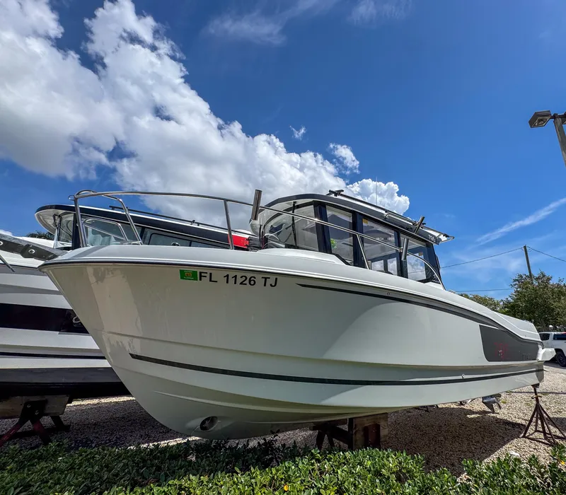 Slide: The Image of 2022 Jeanneau NC795 Sport boat displayed outdoors under a blue sky. - 2