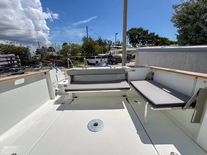 Slide: The Image of 2022 Jeanneau NC795 Sport boat deck with seating, under a clear blue sky. - 22