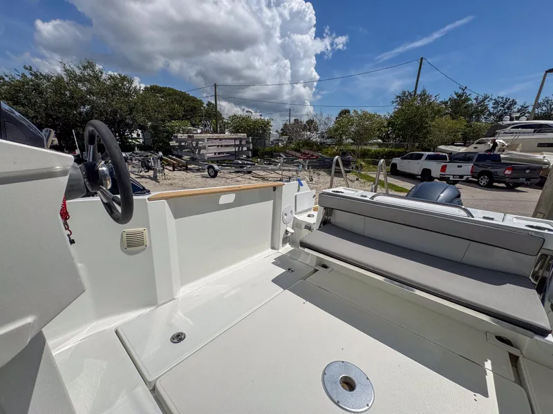 Slide: The Image of 2022 Jeanneau NC795 Sport boat interior with seating and steering wheel under a cloudy sky. - 23