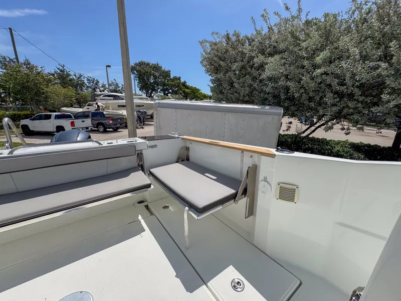 Slide: The Image of 2022 Jeanneau NC795 Sport boat interior with seating, parked outdoors under clear sky. - 24