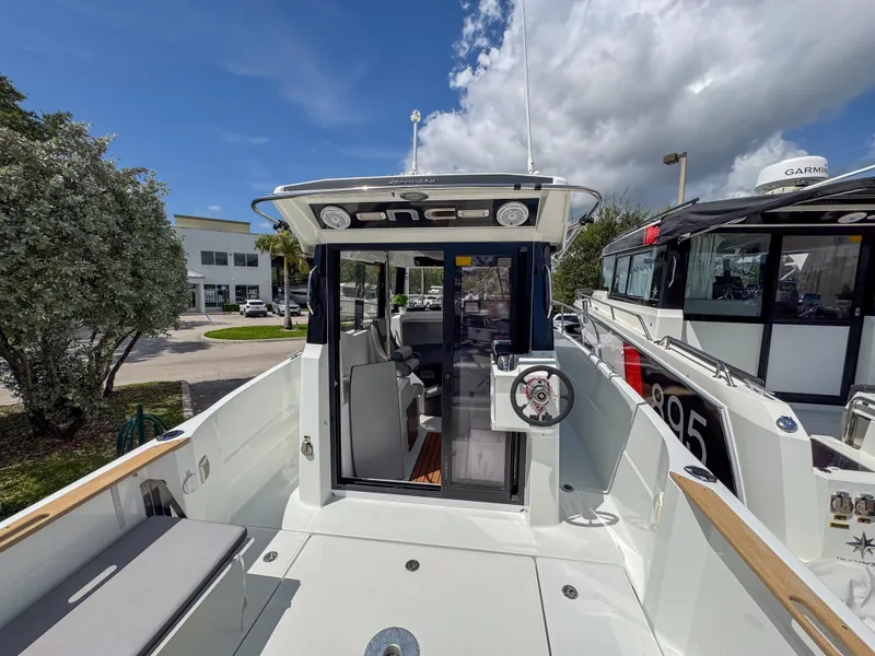 Slide: The Image of 2022 Jeanneau NC795 Sport boat, docked, showcasing spacious deck and modern design under blue sky. - 6