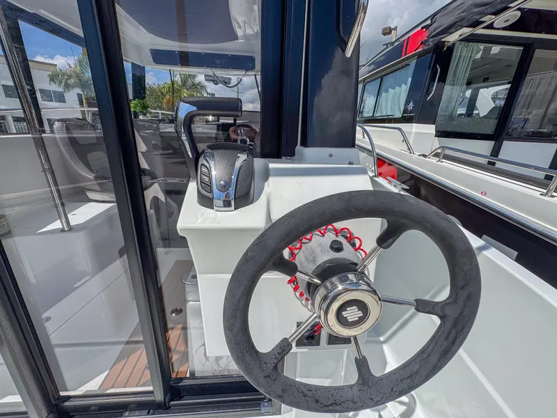 Slide: The Image of 2022 Jeanneau NC795 Sport boat helm with steering wheel and throttle controls. - 9