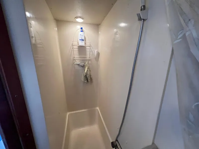 Slide: The Image of Shower area inside 1986 Chris-Craft 381 Catalina boat, featuring a handheld showerhead and storage rack. - 24