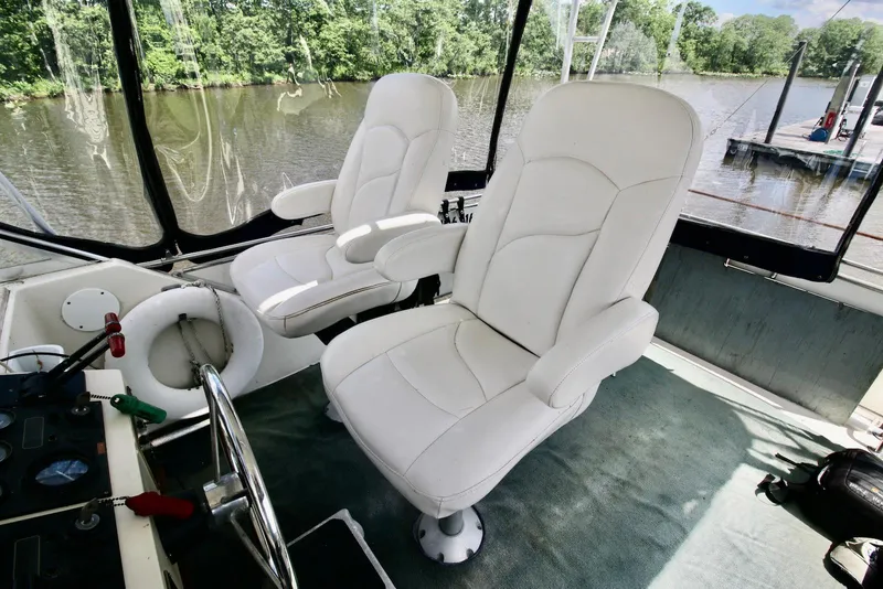 Slide: The Image of 1986 Chris-Craft 381 Catalina interior with white captain chairs and river view. - 6