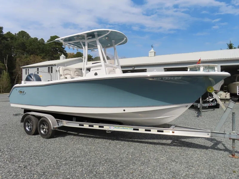 Slide: The Image of 2021 Sea Hunt Ultra 234 boat on trailer, light blue hull, parked outdoors. - 0