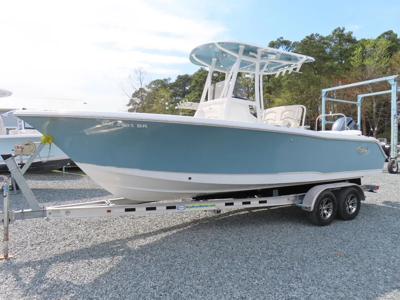 Slide: The Image of 2021 Sea Hunt Ultra 234 boat on trailer, light blue hull, parked outdoors. - 1
