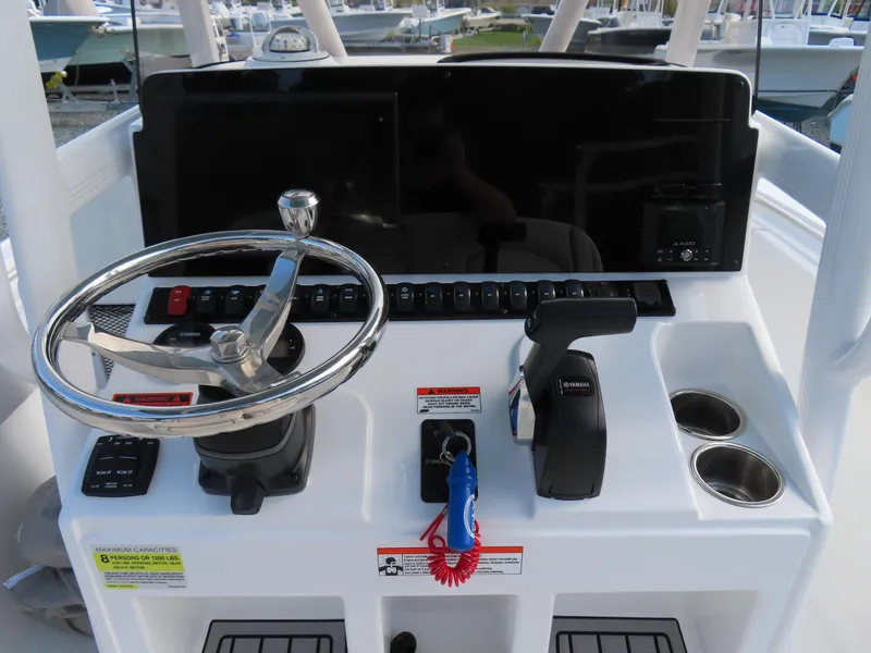 Slide: The Image of 2021 Sea Hunt Ultra 234 helm with steering wheel, controls, and cup holders. - 24