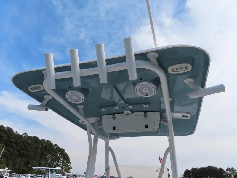 Slide: The Image of 2021 Sea Hunt Ultra 234 boat T-top with rod holders and speakers against blue sky. - 29