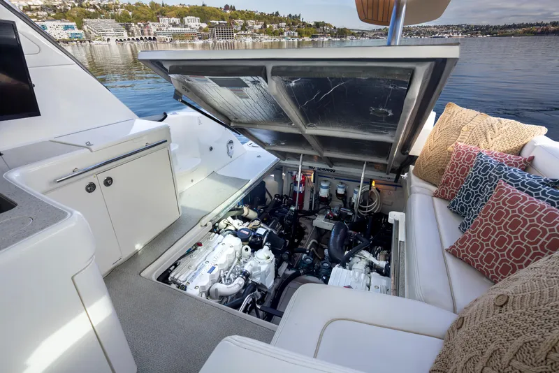 Slide: The Image of 2010 Sea Ray Sundancer engine compartment open, revealing machinery, with seating and cushions nearby. - 45