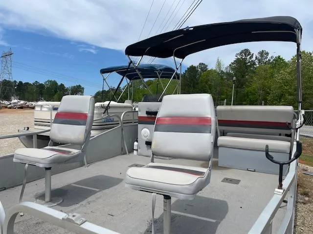 Slide: The Image of 1992 Leisure Island boat with seating, canopy, and open deck, set against a wooded backdrop. - 6