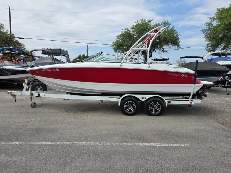 The Image of 2008 Cobalt 220 boat on trailer, red and white design, parked outdoors. - 1