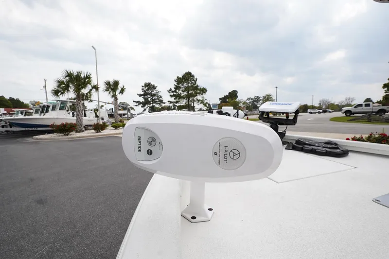 Slide: The Image of 2022 Avid 21 FS boat with a white deck and mounted equipment, parked outdoors. - 12