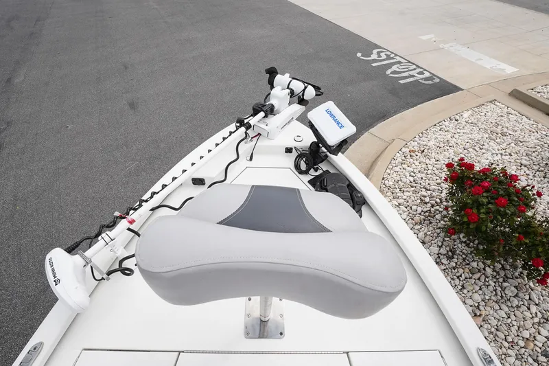 Slide: The Image of Avid 21 FS 2022 boat with trolling motor and seat, parked near curbside flowers. - 13