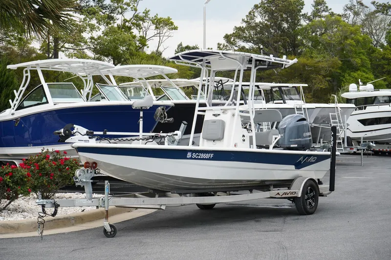 Slide: The Image of 2022 Avid 21 FS boat on trailer, parked in marina with other boats. - 2