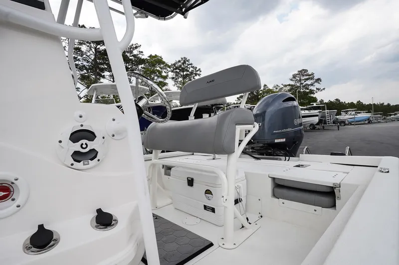Slide: The Image of 2022 Avid 21 FS boat interior with seating and motor, parked outdoors. - 8