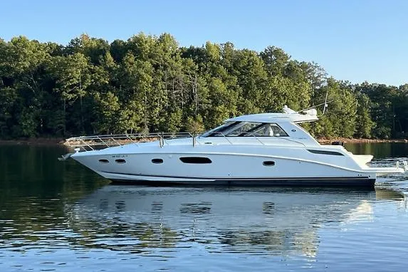 The Image of 2010 Sea Ray 450 Sundancer on calm water with forest backdrop. - 0