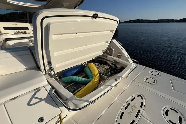 Slide: The Image of 2010 Sea Ray 450 Sundancer boat with open storage compartment, docked by calm waters. - 13