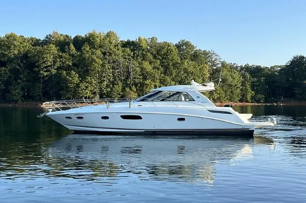 Slide: The Image of 2010 Sea Ray 450 Sundancer yacht on calm lake with forested background. - 2