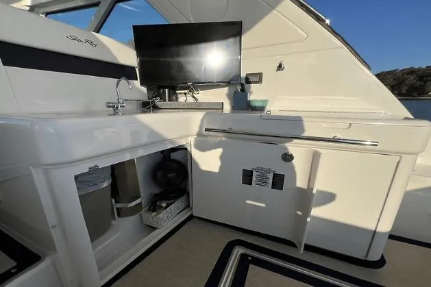 Slide: The Image of 2010 Sea Ray 450 Sundancer yacht interior with kitchenette and TV setup. - 21