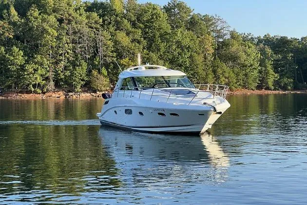 Slide: The Image of 2010 Sea Ray 450 Sundancer cruising on a serene lake with lush green trees. - 3