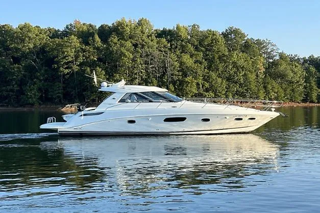 Slide: The Image of 2010 Sea Ray 450 Sundancer yacht cruising on a calm lake with forested shoreline. - 5