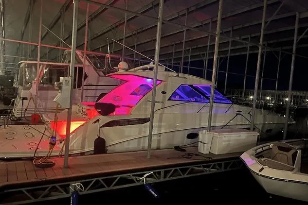 Slide: The Image of 2010 Sea Ray 450 Sundancer yacht docked at night with colorful interior lighting. - 8