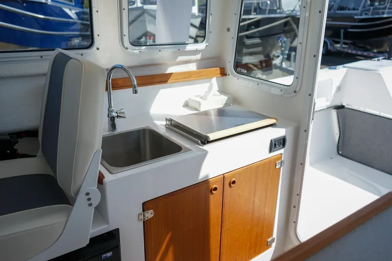 Slide: The Image of Interior of 2022 C-Dory 22' Cruiser featuring a compact kitchenette with sink and storage. - 19