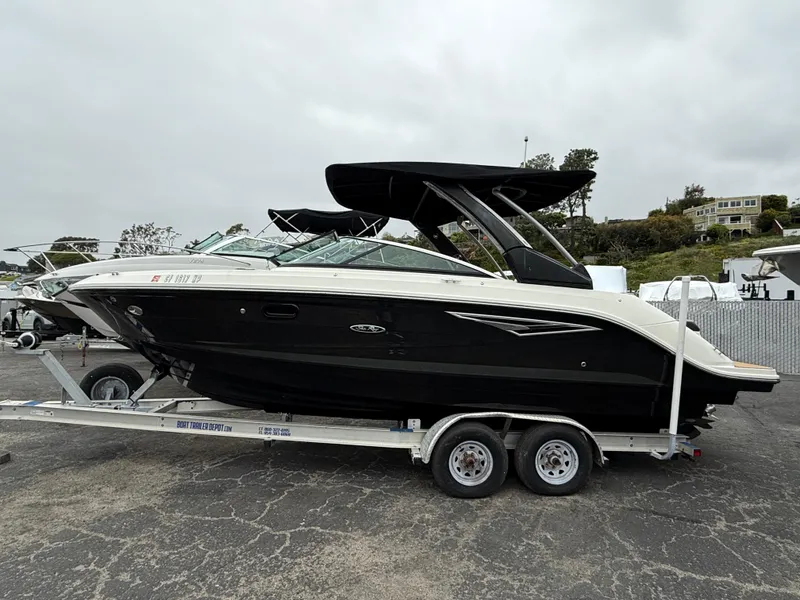 Slide: The Image of 2019 Sea Ray SLX 250 boat on trailer, black hull, parked outdoors. - 1