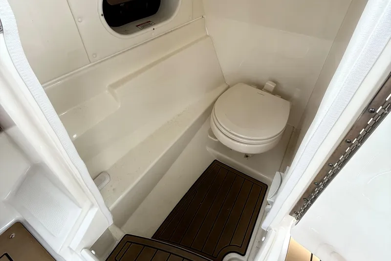 Slide: The Image of 2019 Sea Ray SLX 250 boat interior with compact marine toilet and wooden flooring. - 18