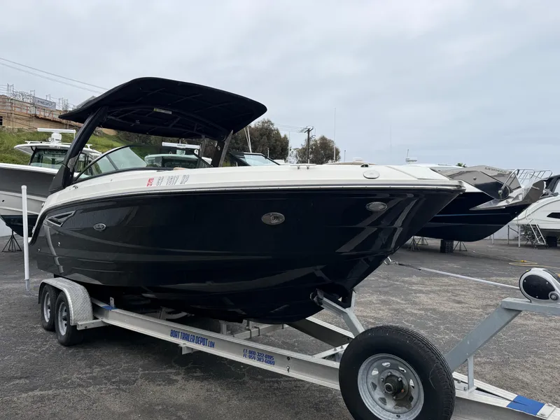 Slide: The Image of 2019 Sea Ray SLX 250 boat on trailer, black hull, parked outdoors. - 2
