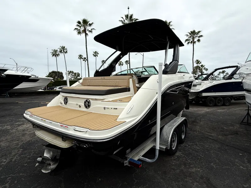Slide: The Image of 2019 Sea Ray SLX 250 boat on trailer, parked outdoors with palm trees in background. - 5