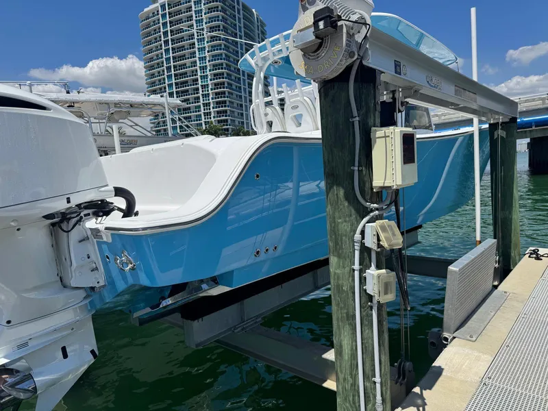 Slide: The Image of 2020 Sportsman Open 352 Center Console boat on lift, docked near high-rise buildings. - 20