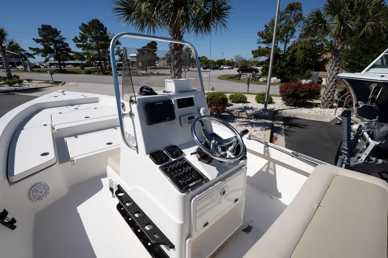 Slide: The Image of 2013 Pathfinder 2400 TRS boat console with steering wheel, surrounded by palm trees. - 13