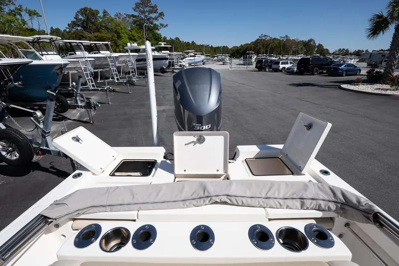 Slide: The Image of 2013 Pathfinder 2400 TRS boat with open storage compartments and motor, parked in a marina. - 6