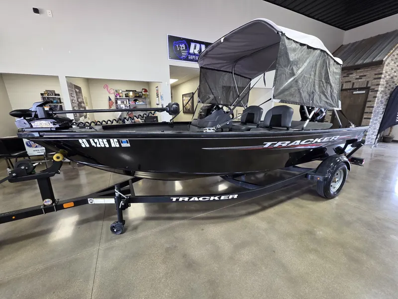 Slide: The Image of 2024 Tracker Super Guide V-16 SC boat with canopy on display indoors. - 2