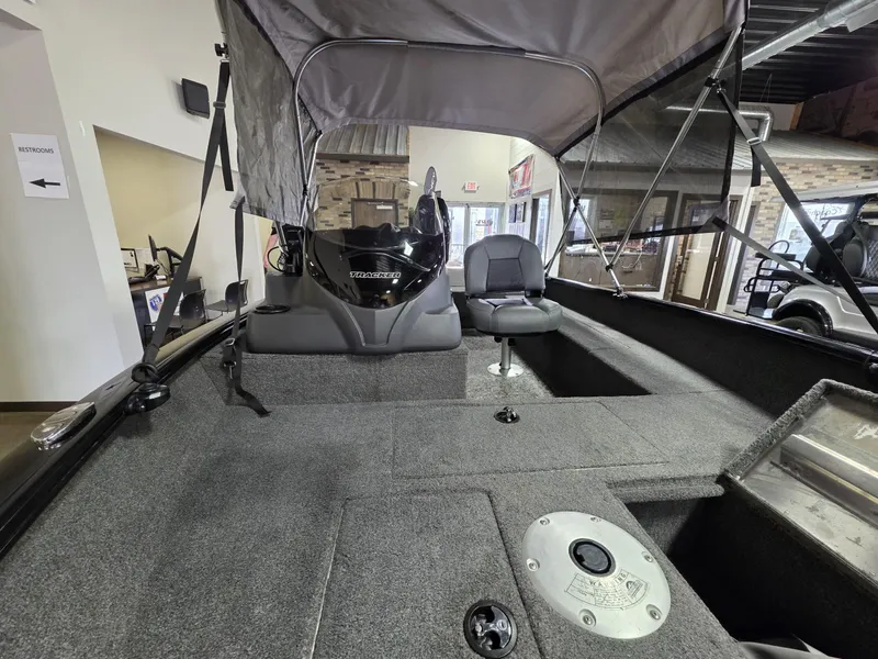 Slide: The Image of 2024 Tracker Super Guide V-16 SC boat interior with seating and canopy in showroom. - 7