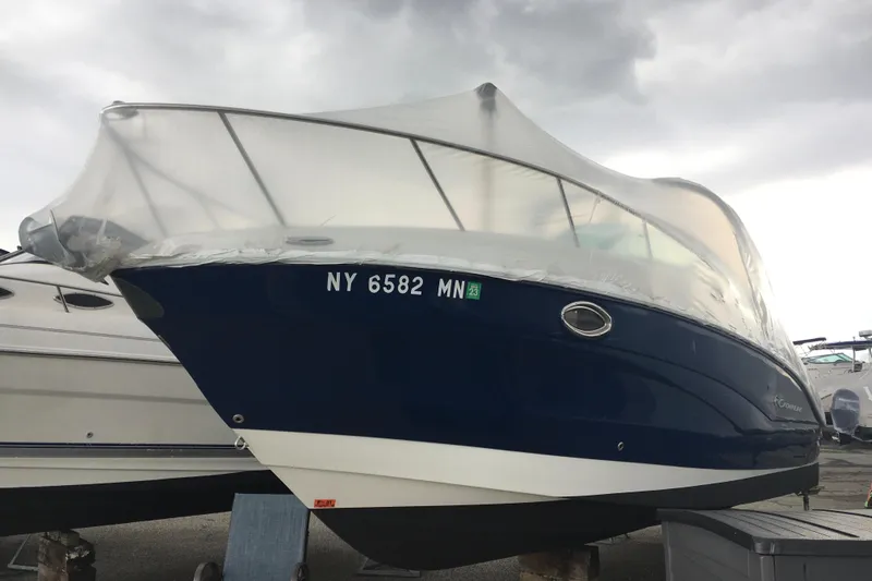 Slide: The Image of 2018 Crownline 264 CR boat with protective cover, docked under cloudy skies. - 1