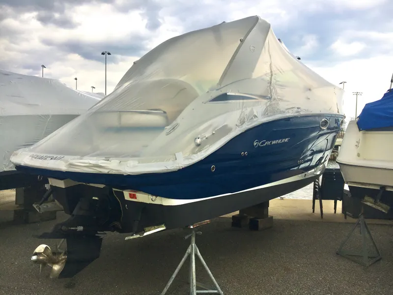 Slide: The Image of 2018 Crownline 264 CR boat covered, stored on a stand, under cloudy skies. - 2
