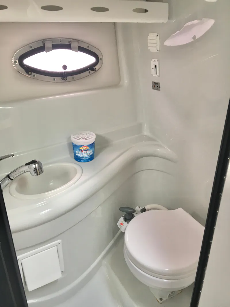 Slide: The Image of 2018 Crownline 264 CR boat bathroom with sink, toilet, and porthole window. - 23