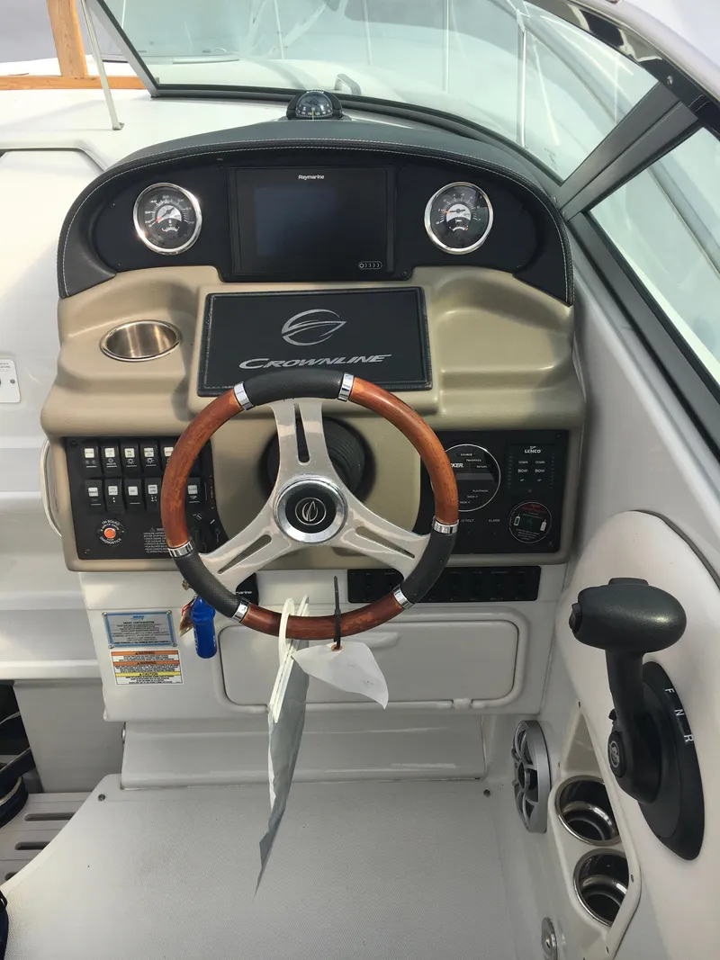 Slide: The Image of 2018 Crownline 264 CR boat helm with wood-accented steering wheel and modern controls. - 7