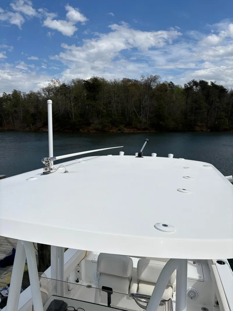 Slide: The Image of 2022 Sea Hunt Ultra 219 boat on a calm lake with a forested shoreline. - 10