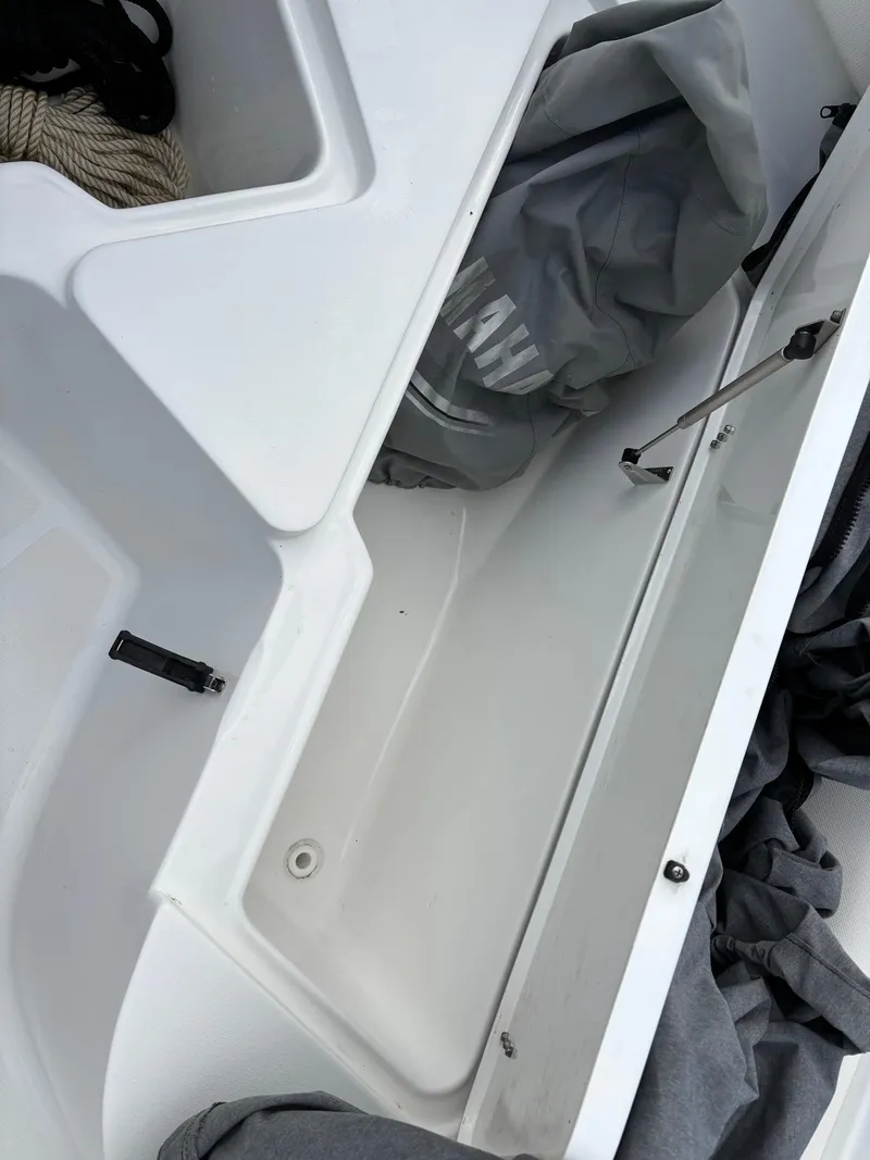 Slide: The Image of 2022 Sea Hunt Ultra 219 boat storage compartment with open hatch and gear inside. - 20