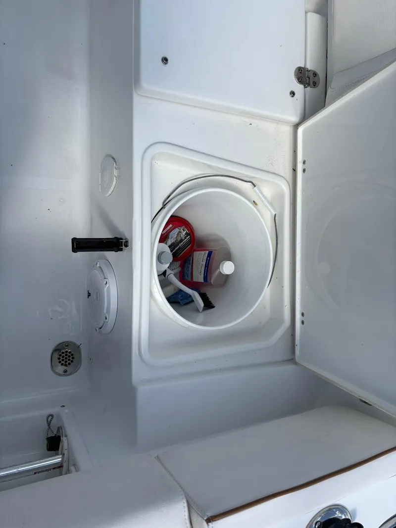 Slide: The Image of Storage compartment on 2022 Sea Hunt Ultra 219 boat, containing cleaning supplies. - 26