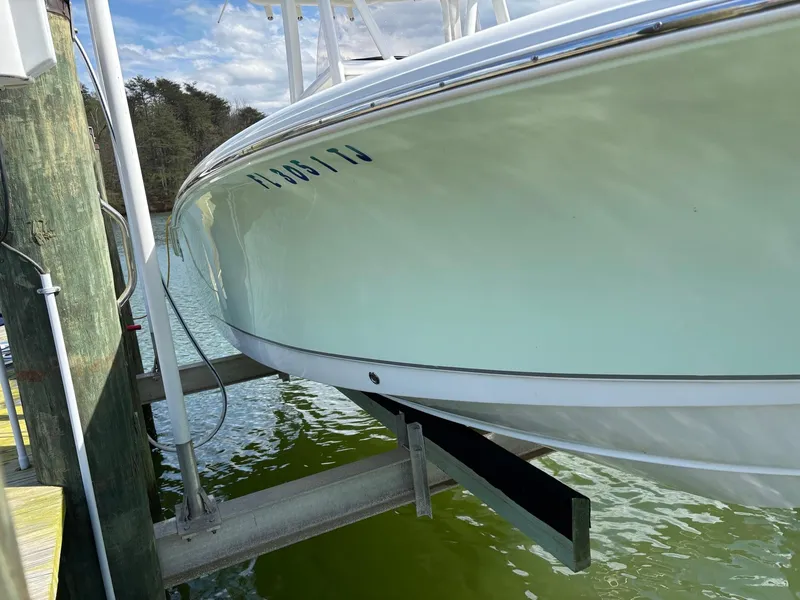 Slide: The Image of 2022 Sea Hunt Ultra 219 boat on lift, docked by green water. - 29