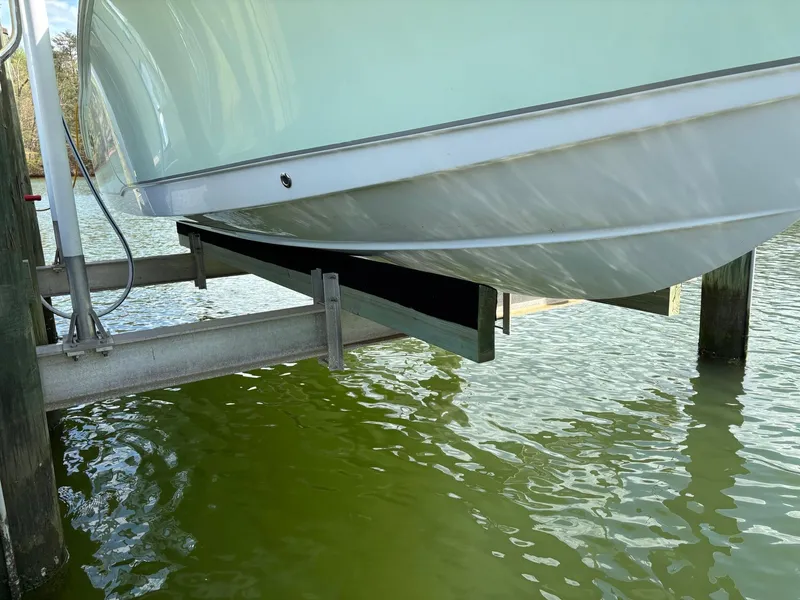 Slide: The Image of 2022 Sea Hunt Ultra 219 boat on lift above green water. - 3