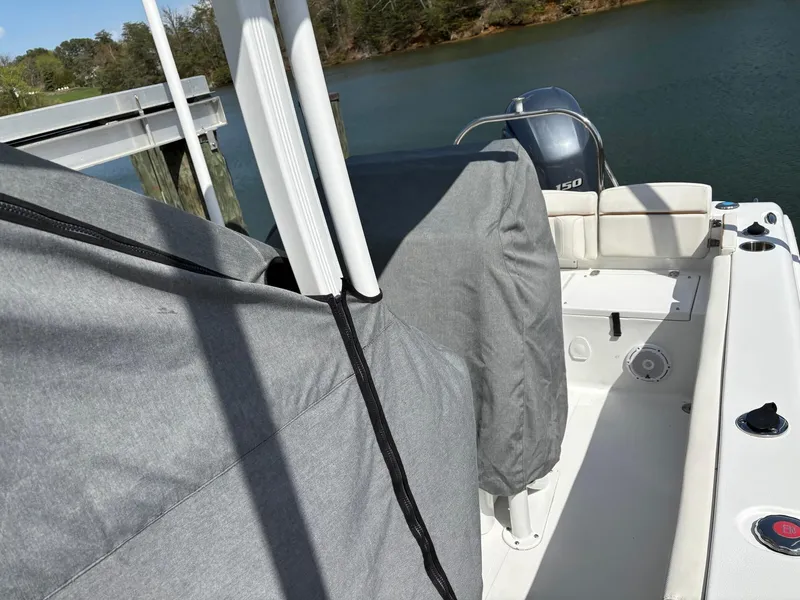 Slide: The Image of 2022 Sea Hunt Ultra 219 boat with covered seats and motor, docked by a serene lake. - 30