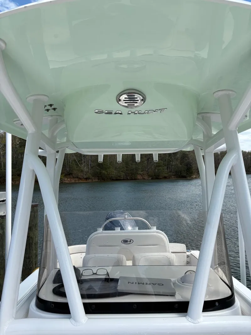 Slide: The Image of 2022 Sea Hunt Ultra 219 boat with canopy, docked on a serene lake. - 7