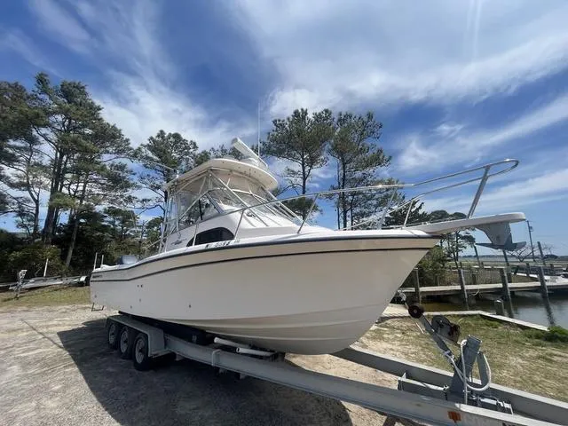 Slide: The Image of 2007 Grady-White 282 Sailfish boat on trailer, parked near trees under a blue sky. - 1