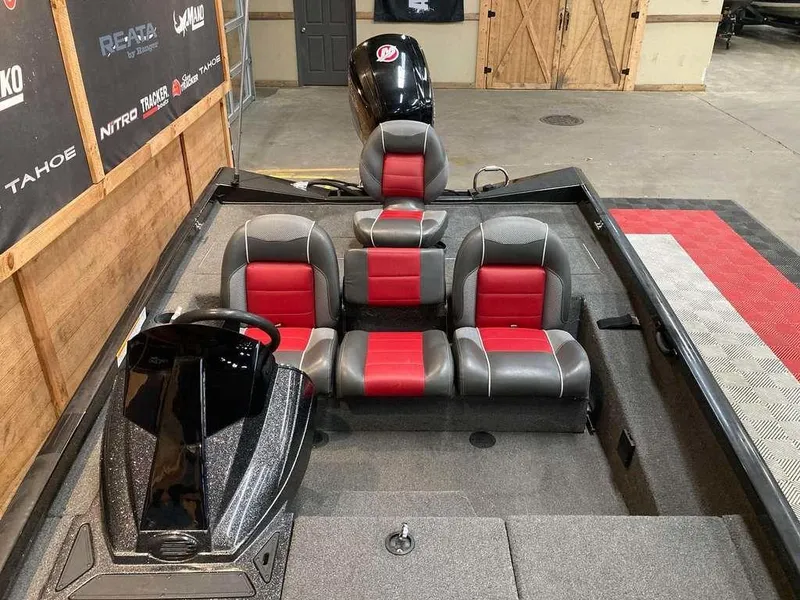 Slide: The Image of 2018 Ranger RT188 boat interior with red and gray seating, steering console, and motor in a showroom. - 7