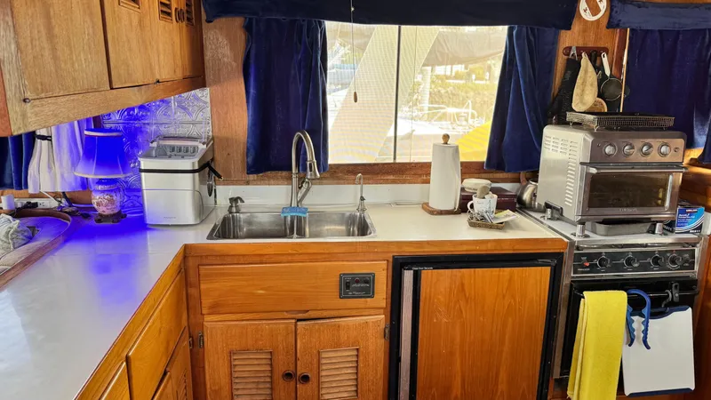 Slide: The Image of 1977 Marine Trader Europa kitchen with wooden cabinets, sink, and appliances. - 14